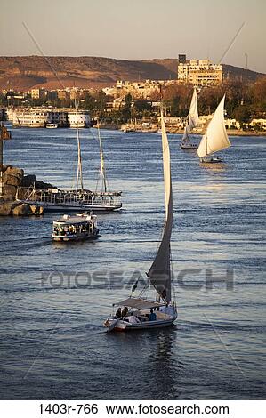 Boats sail the Nile River at Aswan, Egypt in the last rays of the setting sun. View Large Photo Image Stock Photograph - Boats sail the Nile River at Aswan, Egypt in the last rays of the setting sun.. Fotosearch