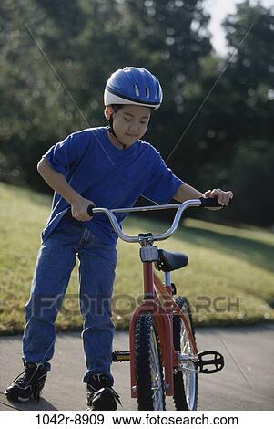 Boy holding a bicycle View Large Photo Image Stock Photo - Boy holding a bicycle. Fotosearch