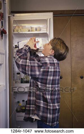 Boy standing by a refrigerator drinking milk from a carton View Large Photo Image Stock Photo - Boy standing by a refrigerator drinking milk from a carton. Fotosearch