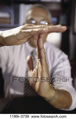 Stock Photo - Businessman gesturing timeout with his hands. Fotosearch