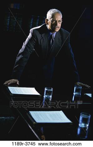 Businessman leaning against a table View Large Photo Image Stock Photography - Businessman leaning against a table. Fotosearch