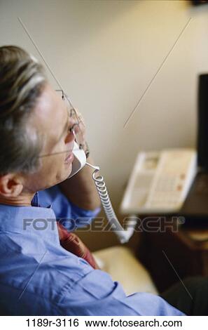 Businessman talking on a landline telephone View Large Photo Image Stock Photograph - Businessman talking on a landline telephone. Fotosearch