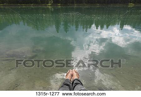Stock Photo - Canada, Alberta, Banff, Bow River, man's feet above calm water. Fotosearch