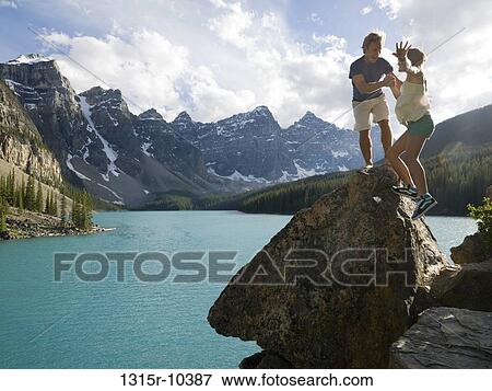 Stock Photo - Canada, Alberta, Banff National Park, father and daughter standing on rock overlooking Moraine Lake. Fotosearch