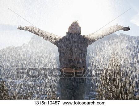 Stock Photo - Canada, Alberta, Banff National Park, Man embracing falling snow on cold winter's day. Fotosearch