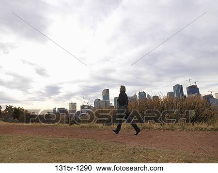 Stock Image - Canada, Alberta, Calgary, businessman walking along river path. Fotosearch