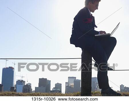 Canada, Alberta, Calgary, Businessman working on laptop in park above city View Large Photo Image Stock Photograph - Canada, Alberta, Calgary, Businessman working on laptop in park above city. Fotosearch