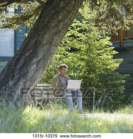 Canada, Alberta, Canmore, Man using laptop computer in front of mountain home View Large Photo Image Stock Photo - Canada, Alberta, Canmore, Man using laptop computer in front of mountain home. Fotosearch