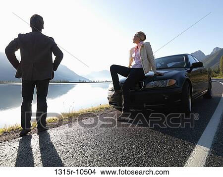 Canada, Alberta, Couple beside car at edge of mountain road View Large Photo Image Picture - Canada, Alberta, Couple beside car at edge of mountain road. Fotosearch
