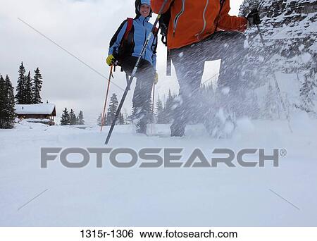 Stock Photograph - Canada, Alberta, couple snowshoeing through mountain meadow. Fotosearch