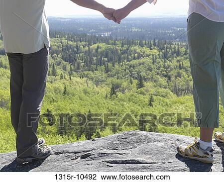 Canada, Alberta, Hikers standing on rock holding hands View Large Photo Image Stock Image - Canada, Alberta, Hikers standing on rock holding hands. Fotosearch