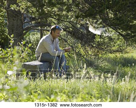 Canada, Alberta, man sitting at stone bench text messaging View Large Photo Image Stock Image - Canada, Alberta, man sitting at stone bench text messaging. Fotosearch
