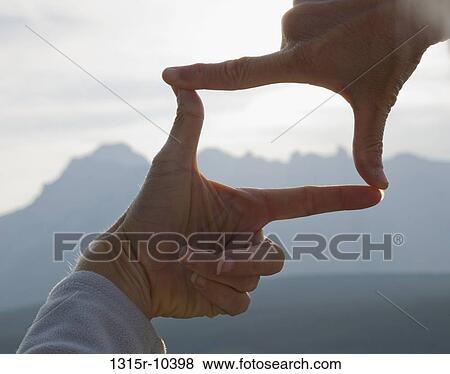Stock Photo - Canada, Alberta, Man's hands framing distant mountain landscape. Fotosearch