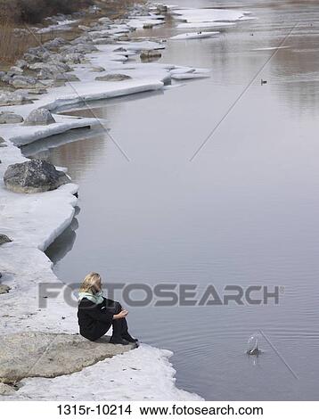 Canada, Alberta, Woman tosses rock in quiet pond from icy bank View Large Photo Image Picture - Canada, Alberta, Woman tosses rock in quiet pond from icy bank. Fotosearch