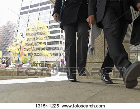 Canada, Calgary, Two businessmen walking through downtown plaza, holding documents, low section View Large Photo Image Stock Photography - Canada, Calgary, Two businessmen walking through downtown plaza, holding documents, low section. Fotosearch