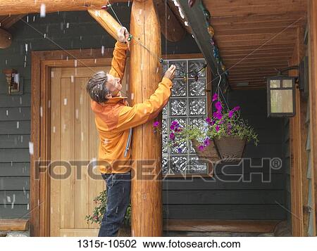 Canada, Man hanging Christmas lights on porch View Large Photo Image Stock Image - Canada, Man hanging Christmas lights on porch. Fotosearch