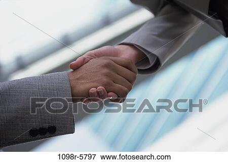 Stock Photo - Close-up of a businessman shaking hands with a businesswoman. Fotosearch