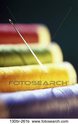 Stock Image - Close-up of a needle on spools of colored thread. Fotosearch