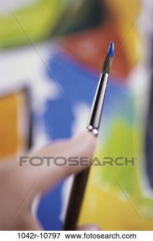 Stock Photo - Close-up of a person holding a paintbrush. Fotosearch