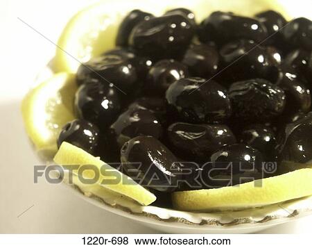 Stock Photo - Close-up of a plate full of black olives and lemon slices. Fotosearch