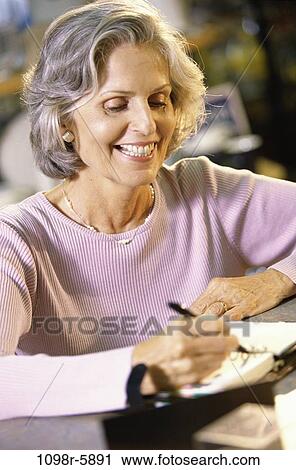 Stock Image - Close-up of a woman writing in an organizer. Fotosearch
