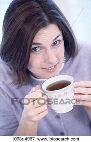 Stock Photo - Close-up of a young woman holding a cup of black coffee. Fotosearch