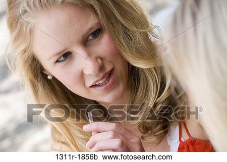 Stock Image - Close-up of a young woman holding a drinking straw. Fotosearch