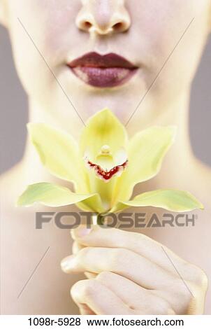 Stock Photo - Close-up of a young woman holding an orchid. Fotosearch