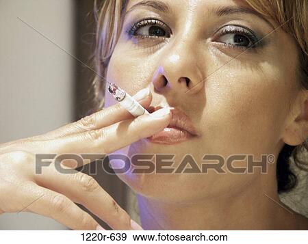 Close-up of a young woman smoking a cigarette View Large Photo Image Stock Photo - Close-up of a young woman smoking a cigarette. Fotosearch