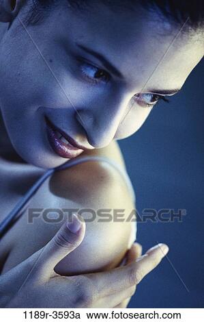 Stock Image - Close-up of a young woman touching her shoulder. Fotosearch