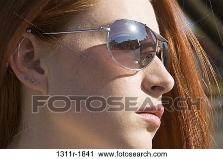 Close-up of a young woman wearing sunglasses View Large Photo Image Stock Image - Close-up of a young woman wearing sunglasses. Fotosearch