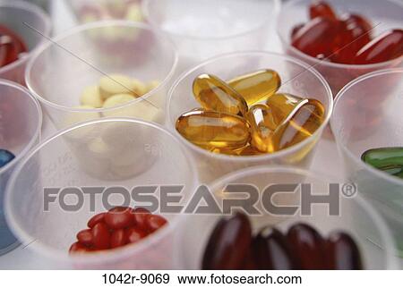 Stock Photo - Close-up of an assortment of tablets and capsules in cups. Fotosearch
