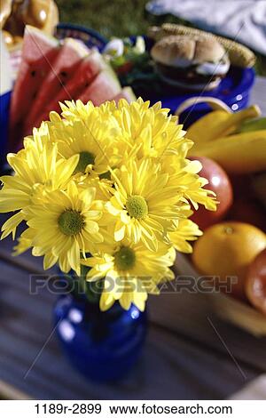 Close-up of flowers in a vase on a picnic table with food View Large Photo Image Stock Photo - Close-up of flowers in a vase on a picnic table with food. Fotosearch
