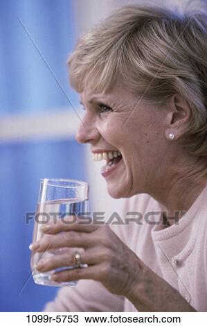 Stock Image - Elderly woman holding a glass of water. Fotosearch