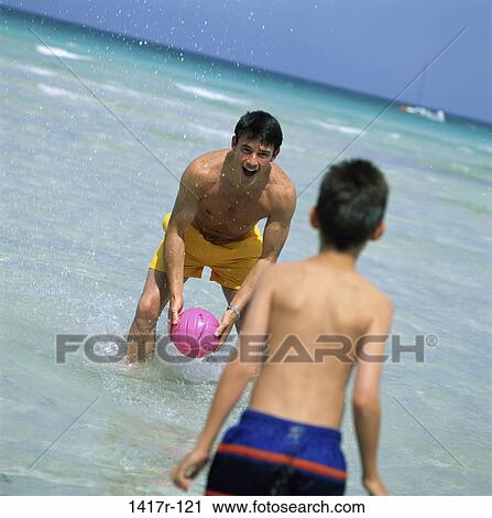 Stock Image - Father and his son playing with a ball on the beach. Fotosearch