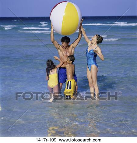 Stock Photo - Father and mother playing with their daughter and son at the beach. Fotosearch