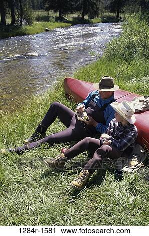 Stock Image - Father and son sitting by a river. Fotosearch