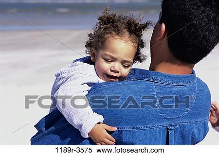 Stock Photography - Father carrying his daughter on the beach. Fotosearch