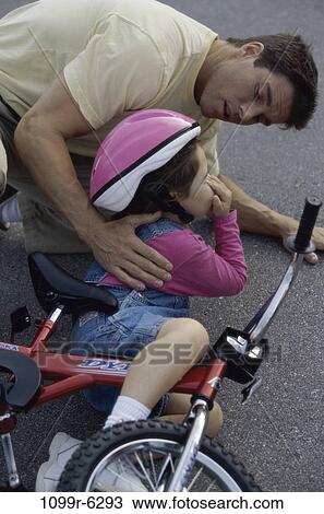 Stock Image - Father consoling his daughter after a fall from her bicycle. Fotosearch