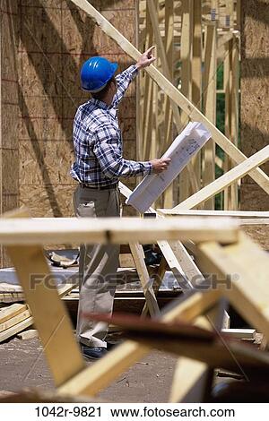 Foreman standing at a construction site holding blueprints View Large Photo Image Stock Image - Foreman standing at a construction site holding blueprints. Fotosearch