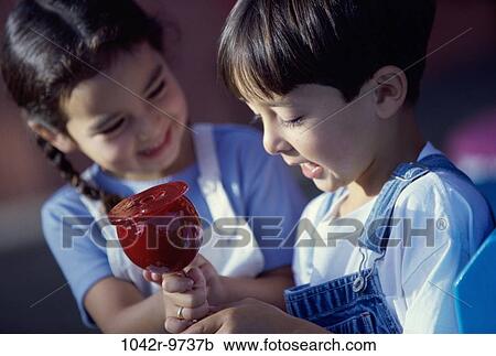 Girl and a boy sitting together holding a candy apple View Large Photo Image Stock Image - Girl and a boy sitting together holding a candy apple. Fotosearch