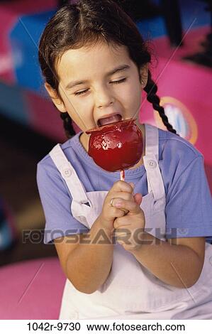 Stock Image - Girl eating a candied apple. Fotosearch