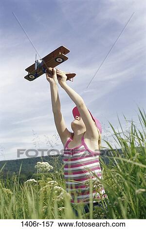 Girl holding a toy airplane in a field View Large Photo Image Stock Photo - Girl holding a toy airplane in a field. Fotosearch
