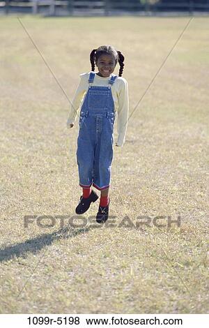 Girl jumping on a field View Large Photo Image Stock Photo - Girl jumping on a field. Fotosearch