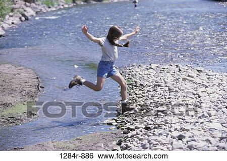 Stock Photograph - Girl jumping over a rock. Fotosearch