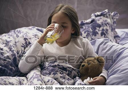 Girl lying in bed drinking juice View Large Photo Image Stock Photo - Girl lying in bed drinking juice. Fotosearch