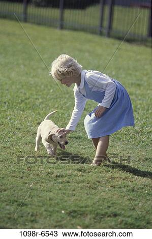 Girl playing with a puppy on the lawn View Large Photo Image Stock Image - Girl playing with a puppy on the lawn. Fotosearch