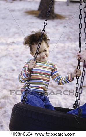 Girl swinging on a tire swing View Large Photo Image Picture - Girl swinging on a tire swing. Fotosearch