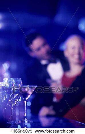 Glasses on a bar with a couple in the background View Large Photo Image Stock Photography - Glasses on a bar with a couple in the background. Fotosearch