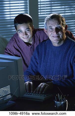 Stock Image - Grandfather working on a computer with his grandson. Fotosearch